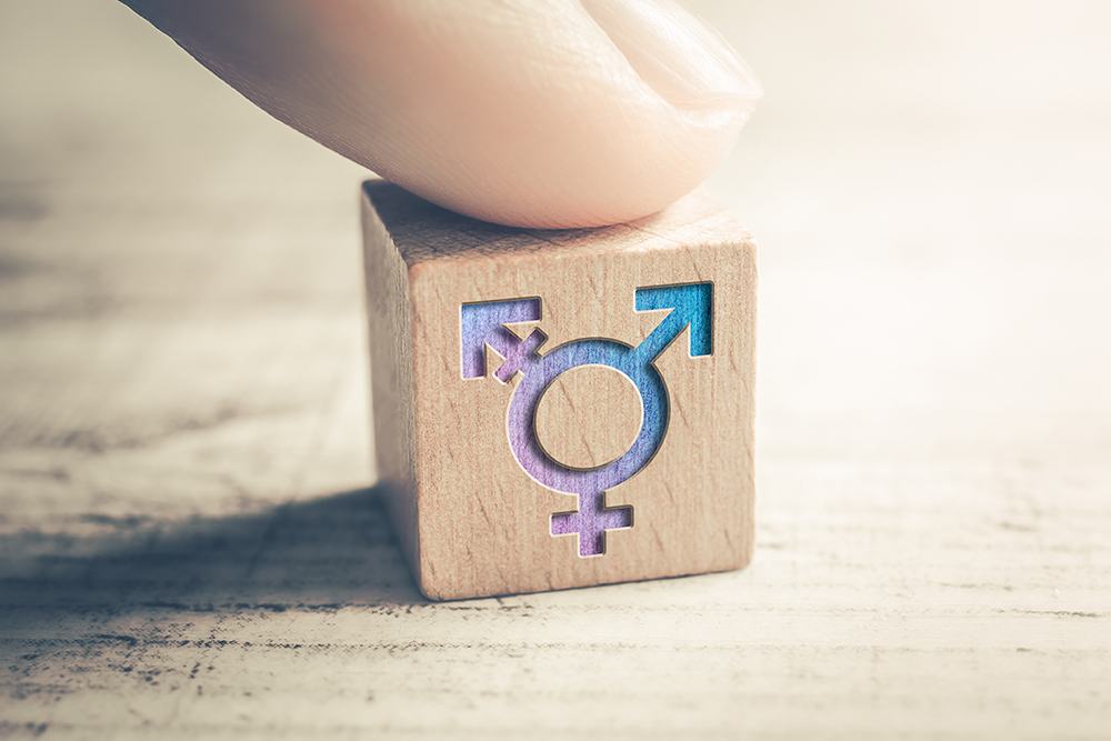 Transgender LGBT oder Intersex Symbol das von einem Finger auf einem Block auf einem Tisch platziert wird